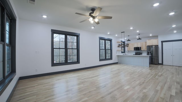 unfurnished living room with ceiling fan, sink, and light hardwood / wood-style floors