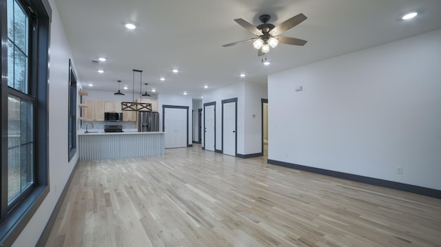 unfurnished living room featuring ceiling fan, sink, and light hardwood / wood-style floors