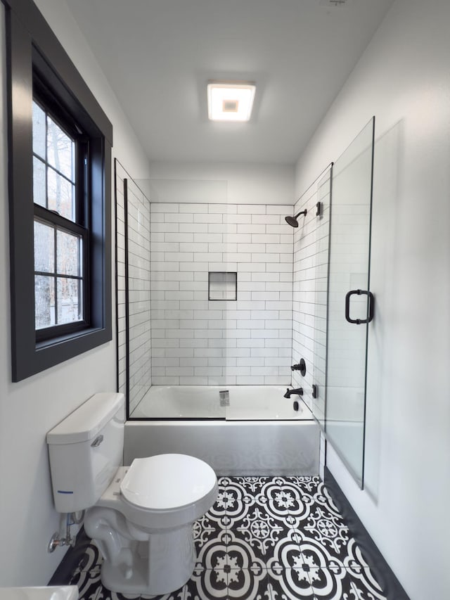 bathroom with combined bath / shower with glass door, tile patterned floors, and toilet