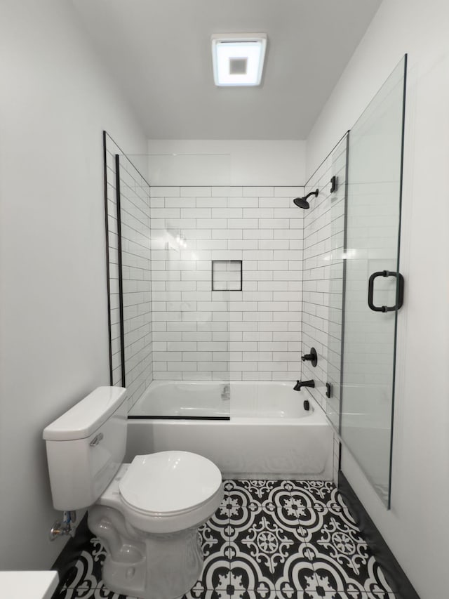 bathroom with tile patterned flooring, bath / shower combo with glass door, and toilet