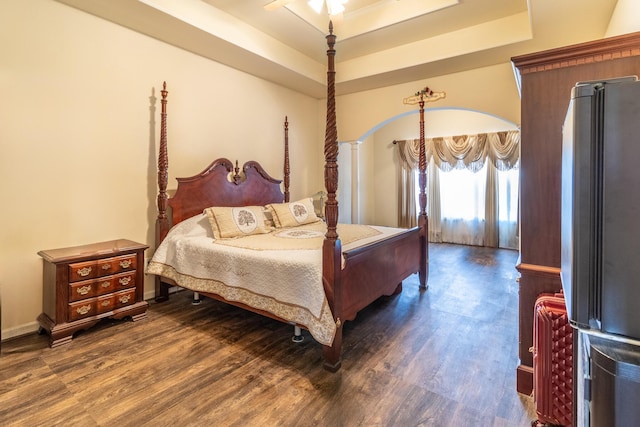 bedroom with dark hardwood / wood-style flooring, a tray ceiling, and stainless steel fridge