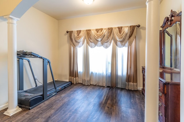 exercise room with dark wood-type flooring and decorative columns