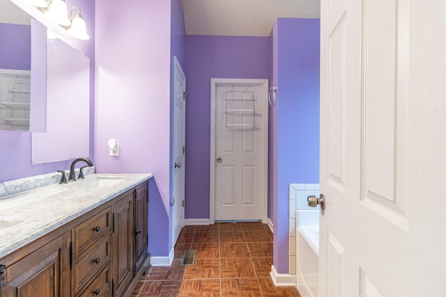 bathroom featuring parquet floors, vanity, and a washtub