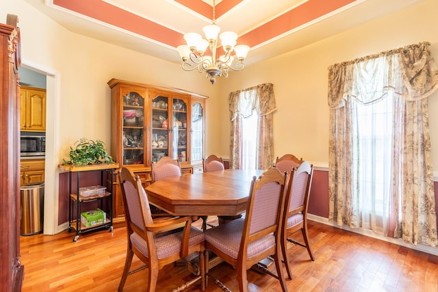 dining room featuring a raised ceiling, light hardwood / wood-style floors, and a wealth of natural light