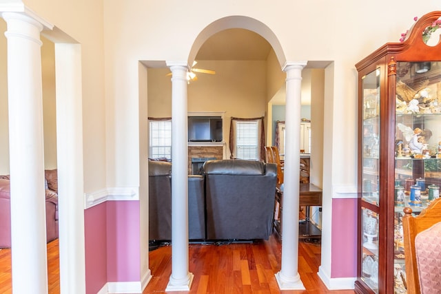 corridor featuring wood-type flooring and decorative columns