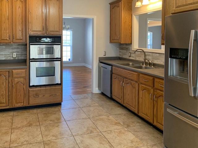 kitchen with appliances with stainless steel finishes, sink, light tile patterned floors, and backsplash