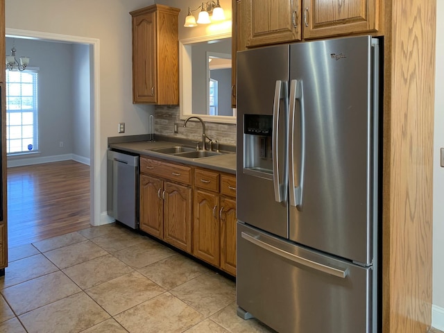 kitchen featuring light tile patterned flooring, sink, an inviting chandelier, appliances with stainless steel finishes, and decorative backsplash