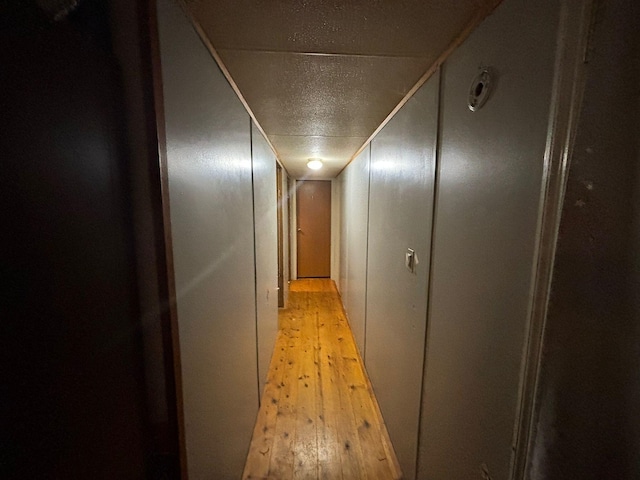 hallway with light hardwood / wood-style floors and a textured ceiling