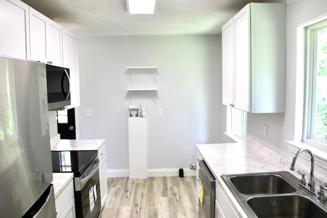 kitchen featuring white cabinetry, sink, stainless steel appliances, and light hardwood / wood-style floors