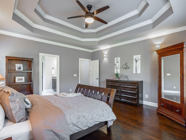 bedroom featuring connected bathroom, dark hardwood / wood-style floors, ornamental molding, and a raised ceiling