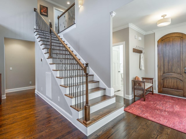 entrance foyer with ornamental molding and dark hardwood / wood-style flooring