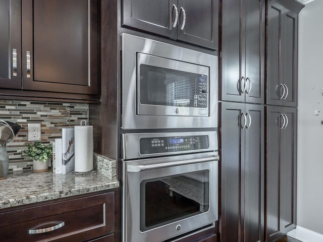 kitchen featuring light stone counters, appliances with stainless steel finishes, dark brown cabinets, and backsplash