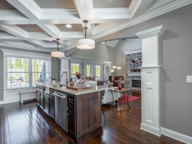 kitchen with dark brown cabinets, stainless steel dishwasher, a kitchen island with sink, and decorative light fixtures