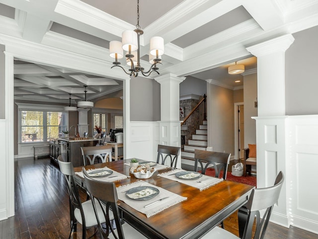 dining space featuring dark wood-type flooring, beam ceiling, coffered ceiling, a chandelier, and ornate columns