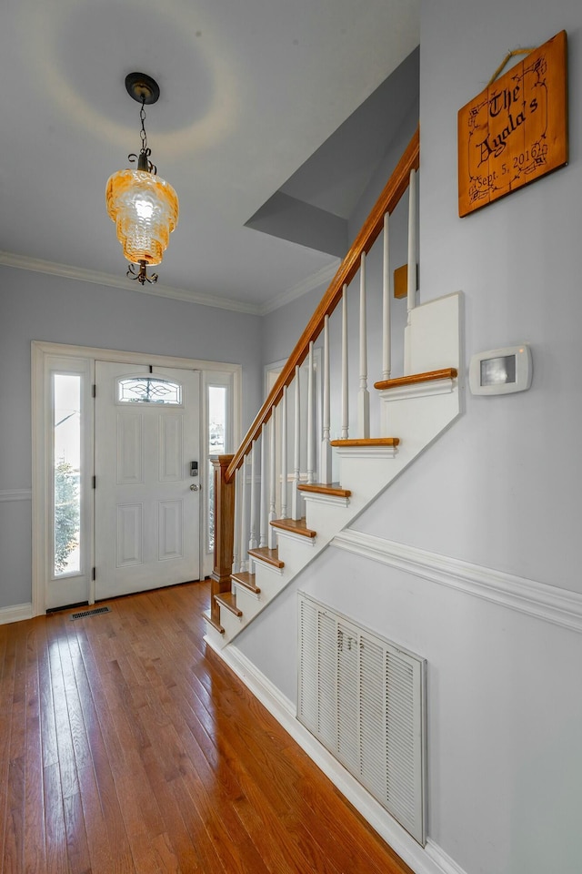 foyer with wood-type flooring and crown molding