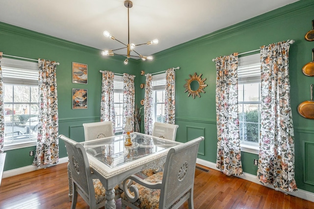 dining room with a notable chandelier, crown molding, and wood-type flooring