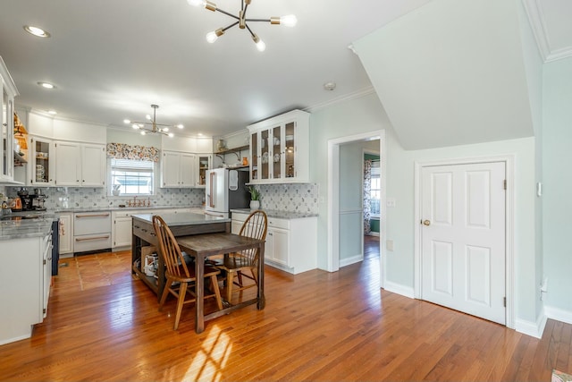 kitchen featuring an inviting chandelier, high end refrigerator, decorative backsplash, and white cabinets