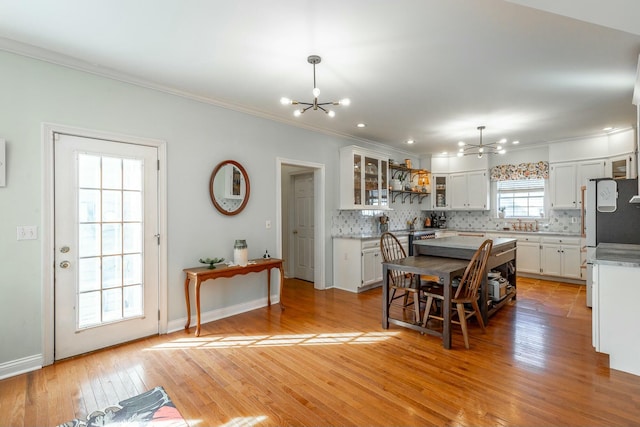 dining area with ornamental molding, a notable chandelier, and light wood-type flooring