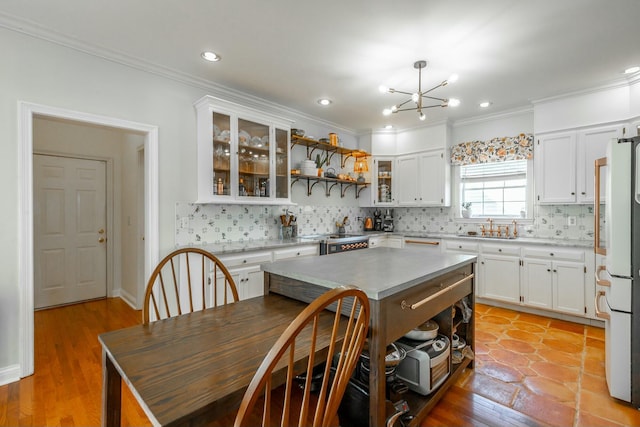 kitchen with tasteful backsplash, white cabinetry, fridge, and a center island