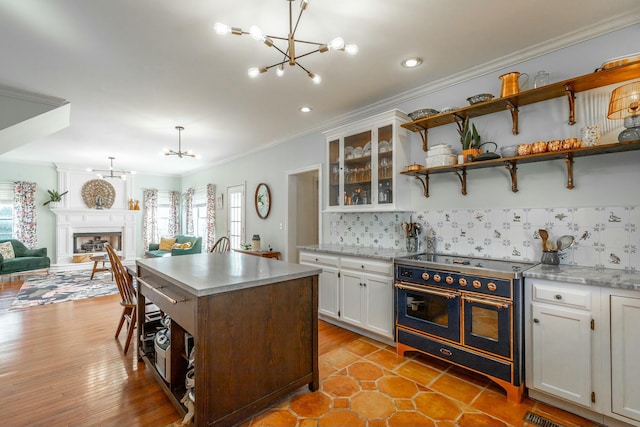 kitchen with white cabinetry, hanging light fixtures, a notable chandelier, a kitchen island, and range with two ovens