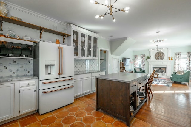 kitchen with pendant lighting, white cabinetry, high end white refrigerator, a chandelier, and a center island with sink