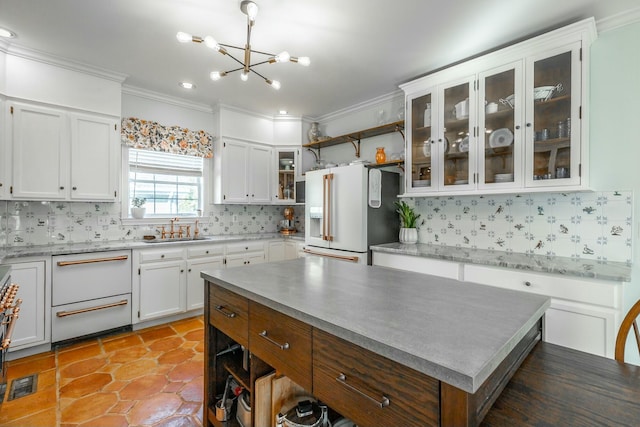 kitchen featuring sink, high end fridge, hanging light fixtures, a center island, and white cabinets