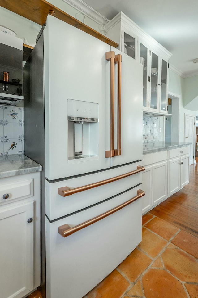 interior space with white cabinetry, light stone counters, tasteful backsplash, ornamental molding, and high end white fridge