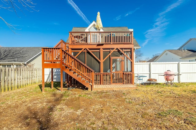 rear view of property featuring a yard, a deck, and a sunroom