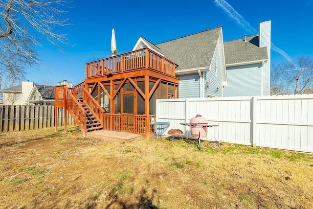 rear view of property with a wooden deck and a lawn