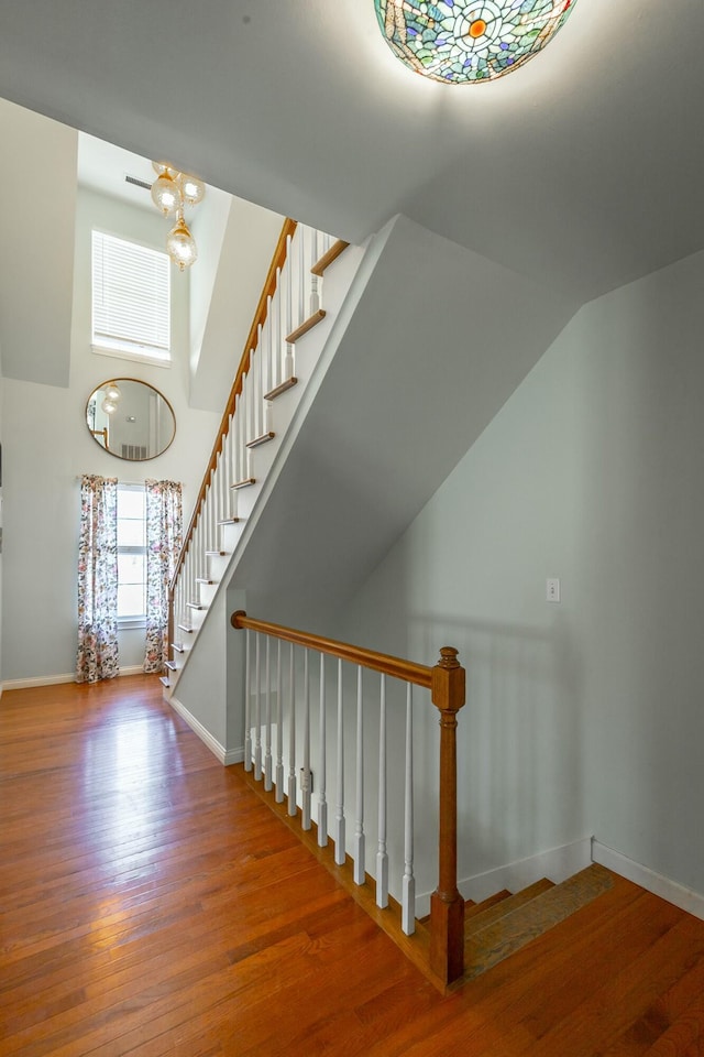 stairs featuring hardwood / wood-style floors and a notable chandelier