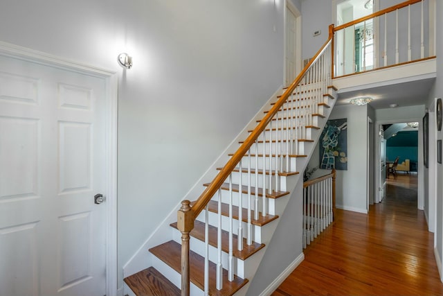 stairs with hardwood / wood-style flooring and a towering ceiling