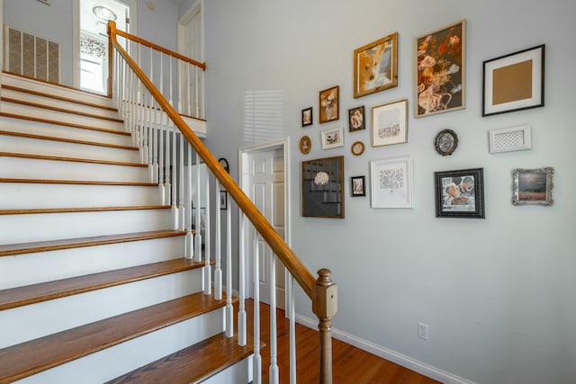 stairs with a high ceiling and hardwood / wood-style floors