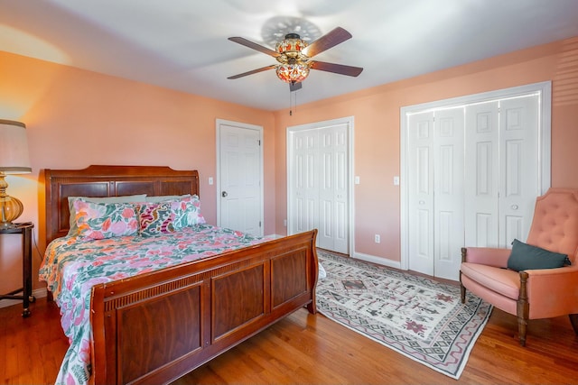 bedroom with two closets, light hardwood / wood-style floors, and ceiling fan