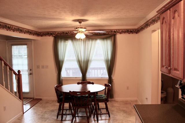 dining area with ornamental molding, a wealth of natural light, and a textured ceiling