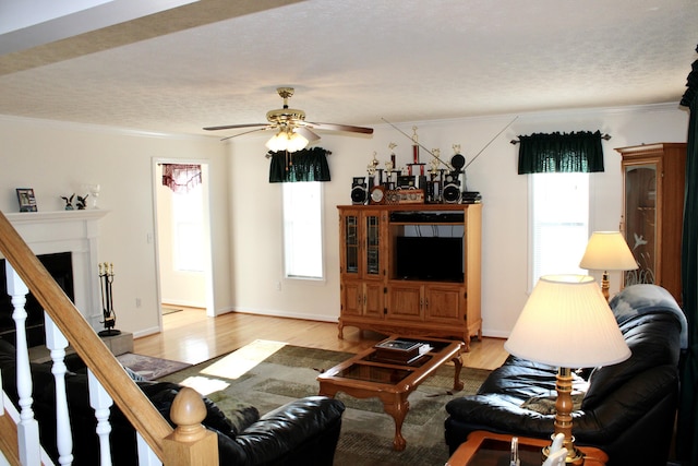 living room with crown molding, light hardwood / wood-style flooring, a textured ceiling, and ceiling fan