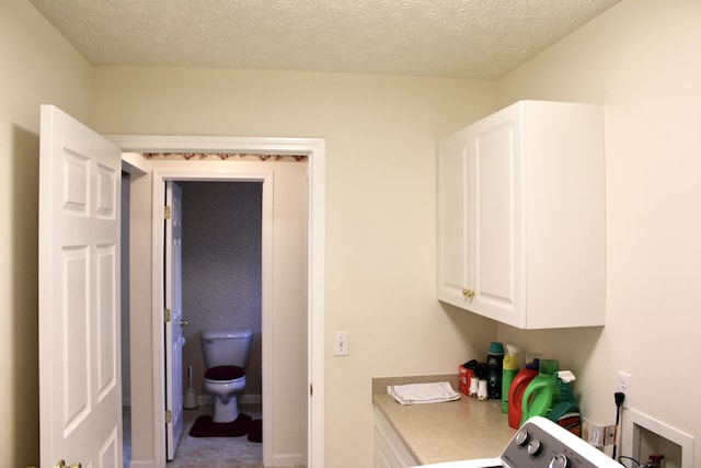 clothes washing area with washer / clothes dryer and a textured ceiling