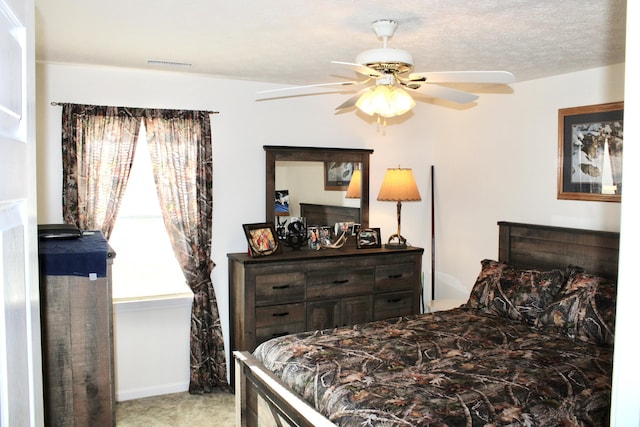 bedroom with ceiling fan, light carpet, and a textured ceiling