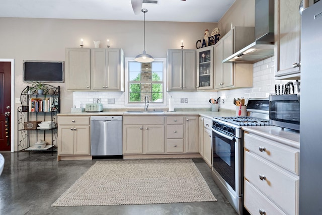 kitchen featuring sink, tasteful backsplash, hanging light fixtures, appliances with stainless steel finishes, and wall chimney range hood