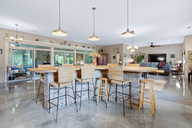 kitchen with pendant lighting, a kitchen breakfast bar, and concrete floors