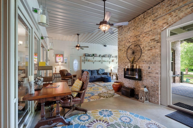 living room with brick wall, concrete floors, and ceiling fan