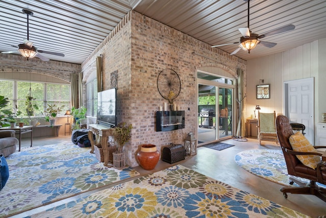 interior space featuring ceiling fan, brick wall, concrete flooring, and a brick fireplace