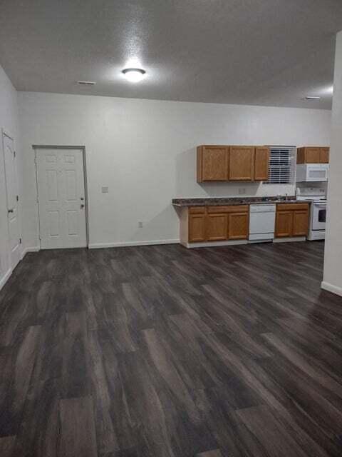 kitchen featuring dark hardwood / wood-style flooring, white appliances, and a textured ceiling