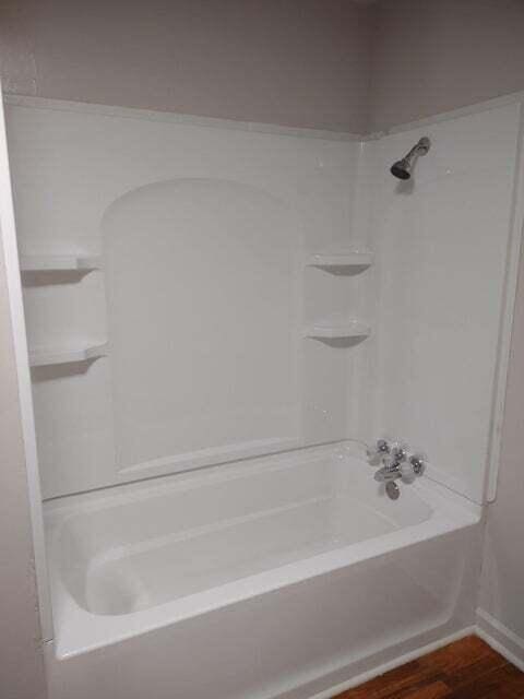 bathroom featuring wood-type flooring and bathtub / shower combination