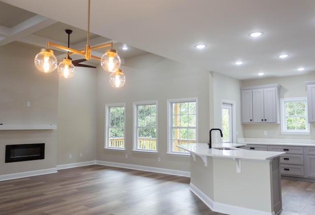 kitchen featuring pendant lighting, sink, a breakfast bar, a kitchen island with sink, and dark hardwood / wood-style flooring