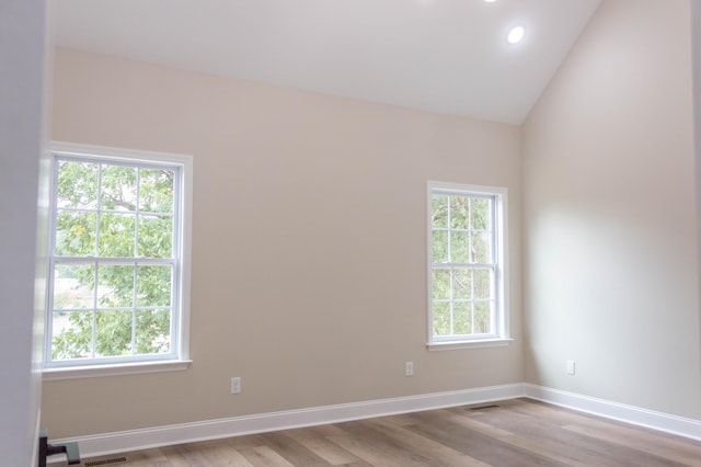 empty room with plenty of natural light, lofted ceiling, and light hardwood / wood-style floors