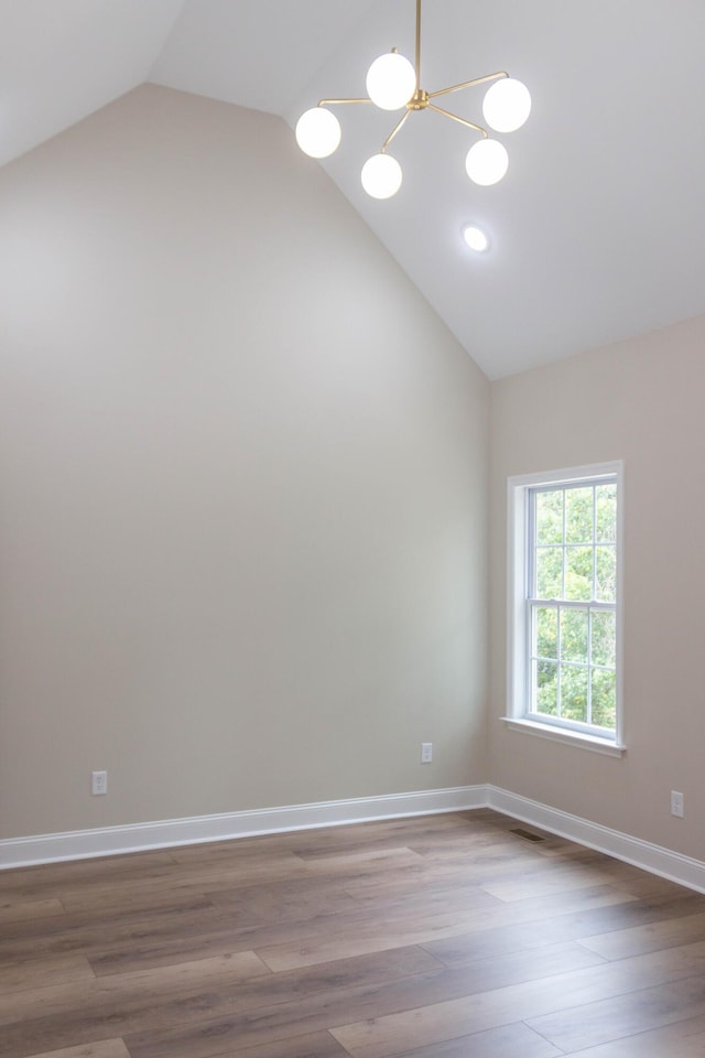 spare room with lofted ceiling, hardwood / wood-style floors, and a notable chandelier