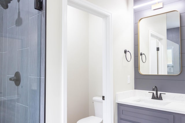 bathroom featuring vanity, a tile shower, and toilet