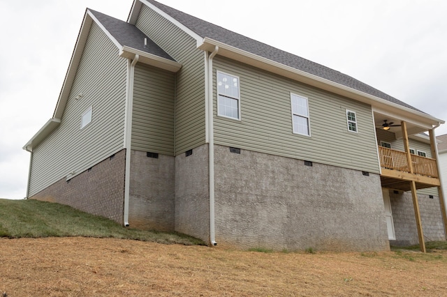 view of side of home featuring ceiling fan, a yard, and a balcony