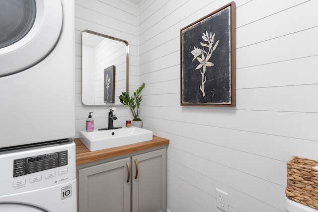 bathroom featuring stacked washer / dryer and vanity