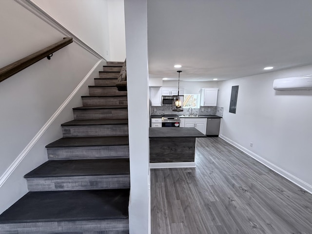 stairway with wood-type flooring, an AC wall unit, and sink